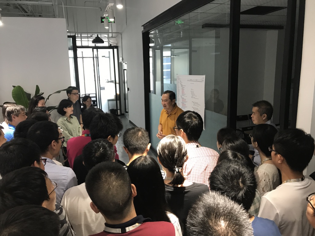 The program team gathered in front of the macro plan posted on the wall